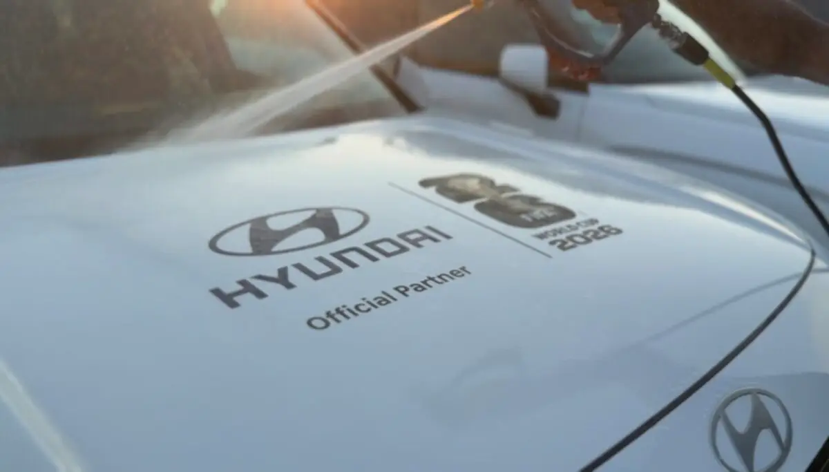 A pressure washer rinses a white Hyundai vehicle with FIFA World Cup 2026 branding.